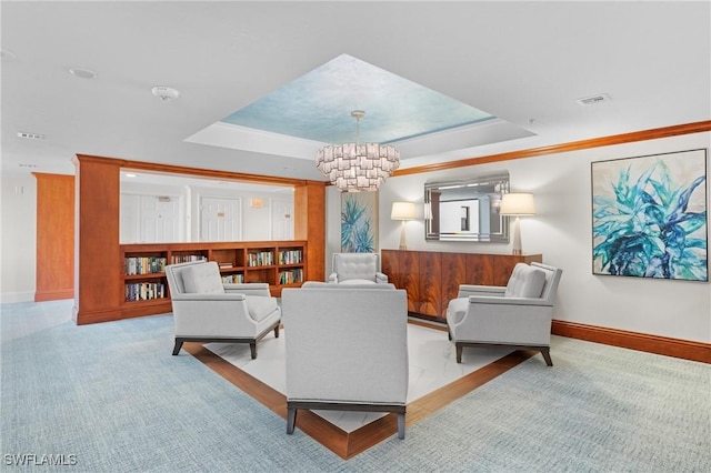 living room featuring a tray ceiling, an inviting chandelier, and ornamental molding