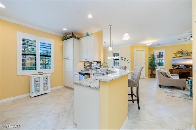 kitchen featuring hanging light fixtures, kitchen peninsula, a kitchen bar, light stone counters, and white cabinets