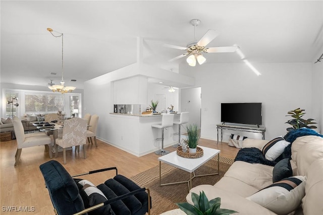 living room featuring ceiling fan with notable chandelier, lofted ceiling, and light hardwood / wood-style flooring