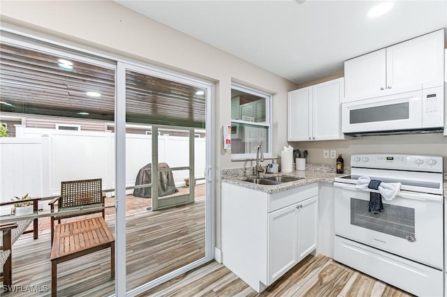 kitchen with white cabinetry, white appliances, sink, and light hardwood / wood-style flooring