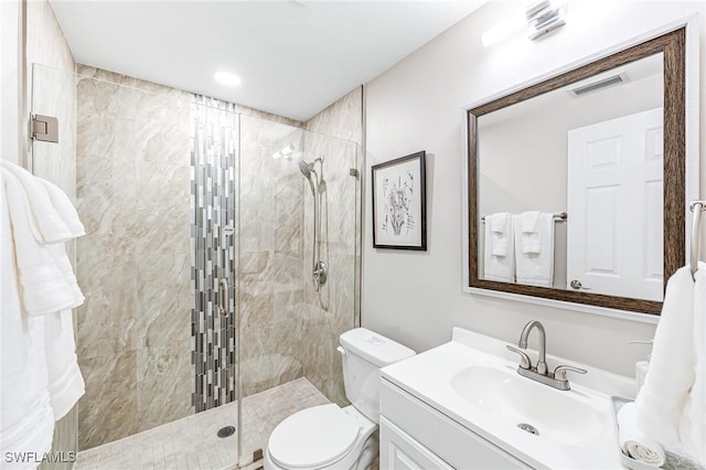 bathroom featuring toilet, vanity, and tiled shower