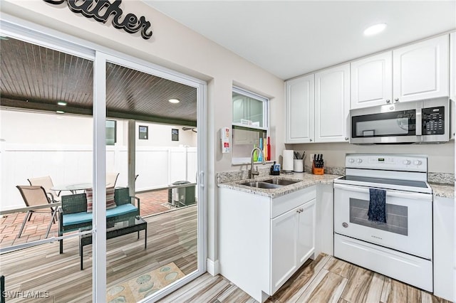 kitchen featuring white cabinetry, light stone countertops, white electric range, and sink