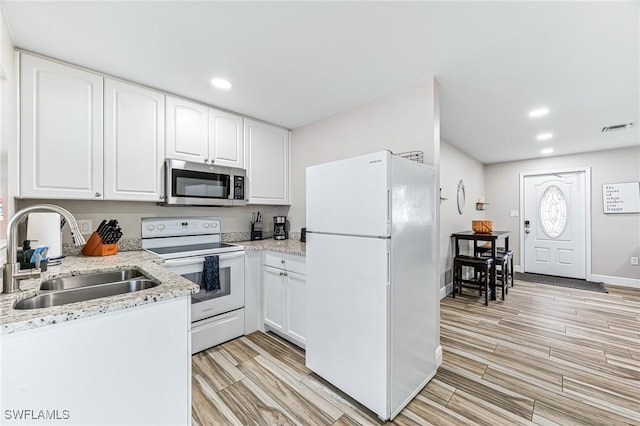 kitchen featuring light stone countertops, sink, white cabinets, and white appliances