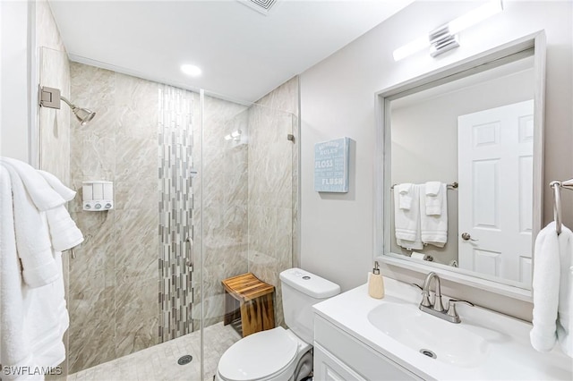 bathroom featuring vanity, a shower with shower door, and toilet