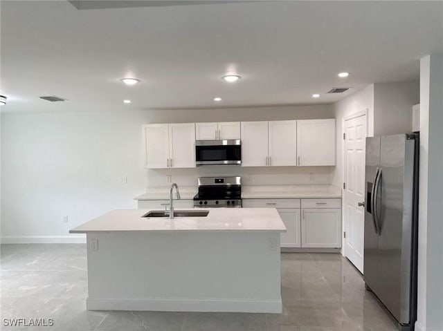 kitchen with white cabinets, sink, stainless steel appliances, and an island with sink