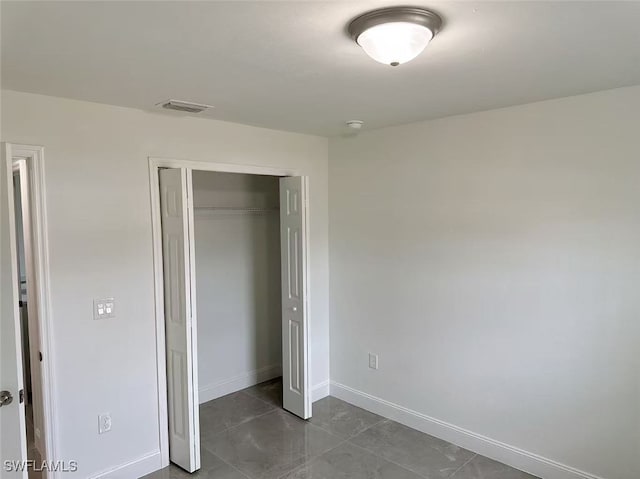 unfurnished bedroom featuring a closet and dark tile patterned floors