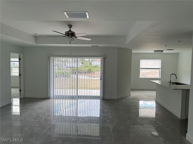 empty room with ceiling fan, a raised ceiling, and sink