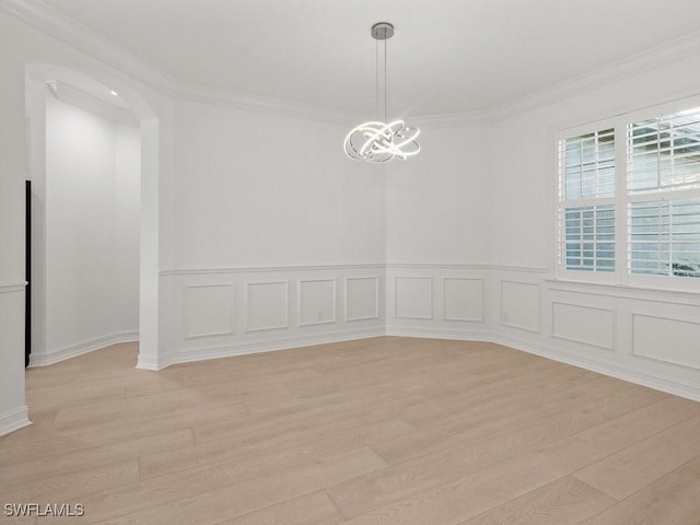 empty room featuring ornamental molding, light hardwood / wood-style floors, and a notable chandelier