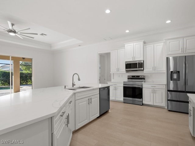 kitchen with stainless steel appliances, white cabinetry, sink, and light wood-type flooring