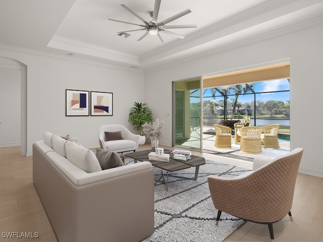 living room featuring crown molding, ceiling fan, a water view, light hardwood / wood-style floors, and a raised ceiling