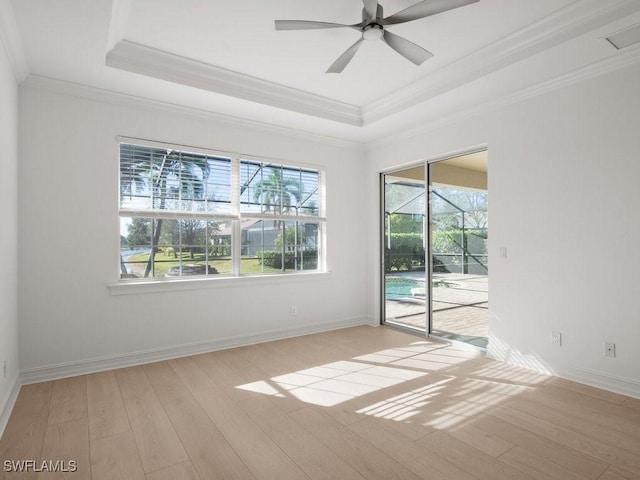 spare room with ceiling fan, ornamental molding, a raised ceiling, and light hardwood / wood-style floors