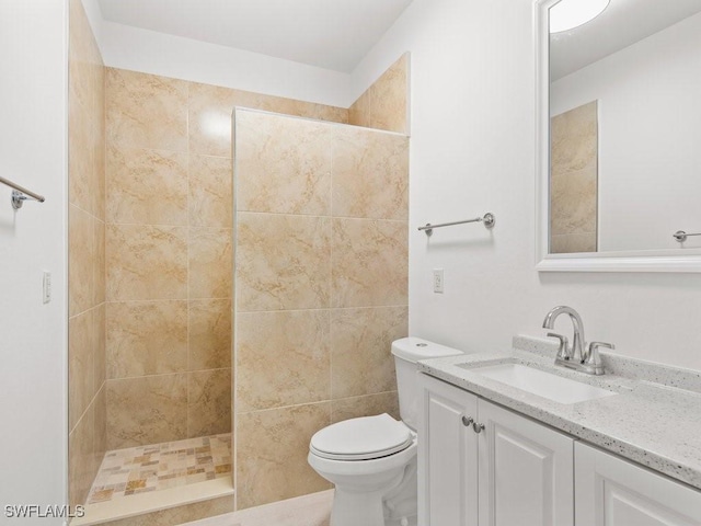 bathroom with vanity, toilet, and a tile shower