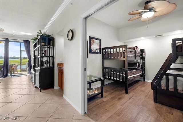 bedroom with ceiling fan, light tile patterned floors, and ornamental molding