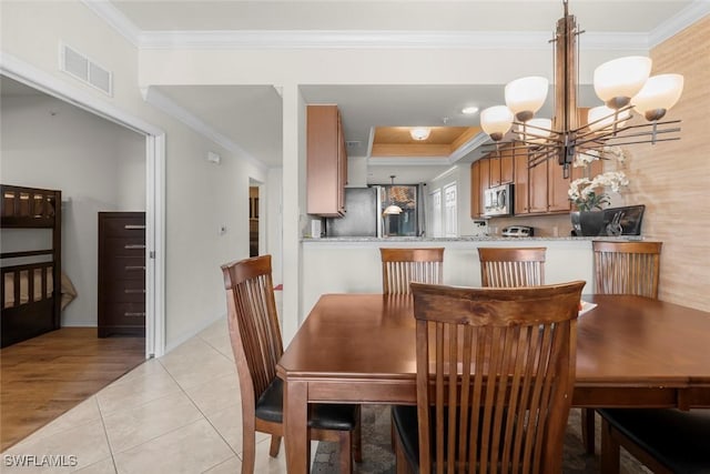 tiled dining room with a notable chandelier and ornamental molding