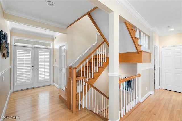 entrance foyer featuring french doors, ornamental molding, and light wood-type flooring