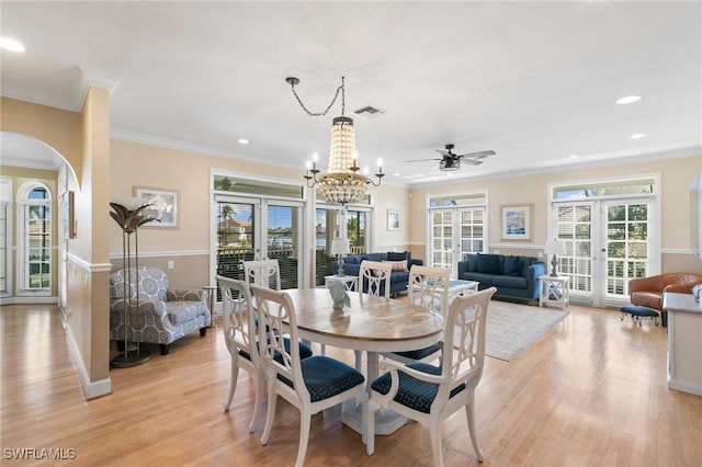 dining area featuring crown molding, french doors, light hardwood / wood-style floors, and ceiling fan with notable chandelier