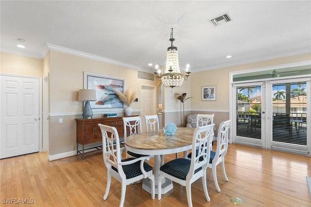 dining space with light wood-type flooring, crown molding, and an inviting chandelier