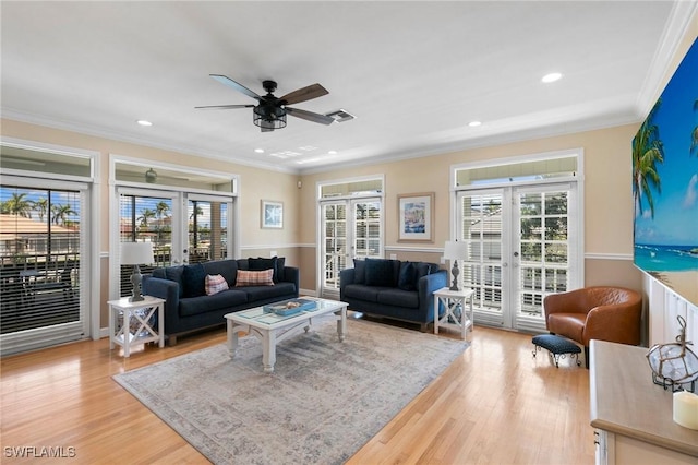 living room with ornamental molding, french doors, a healthy amount of sunlight, and light hardwood / wood-style floors