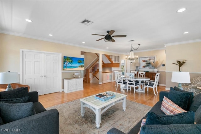 living room featuring ceiling fan with notable chandelier, light wood-type flooring, and crown molding