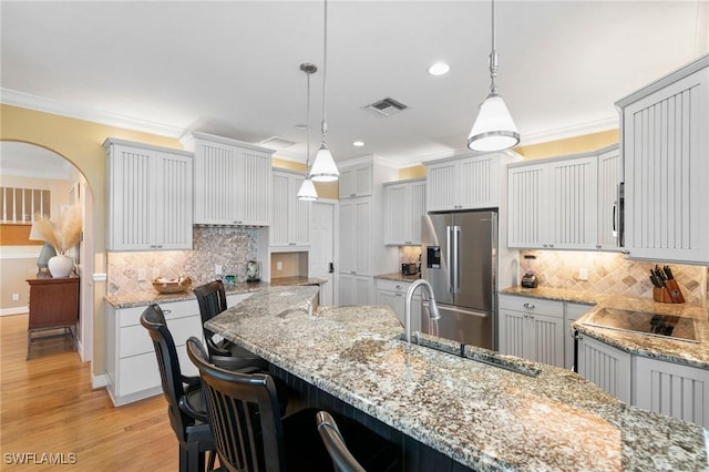 kitchen featuring decorative backsplash, stainless steel fridge with ice dispenser, and hanging light fixtures