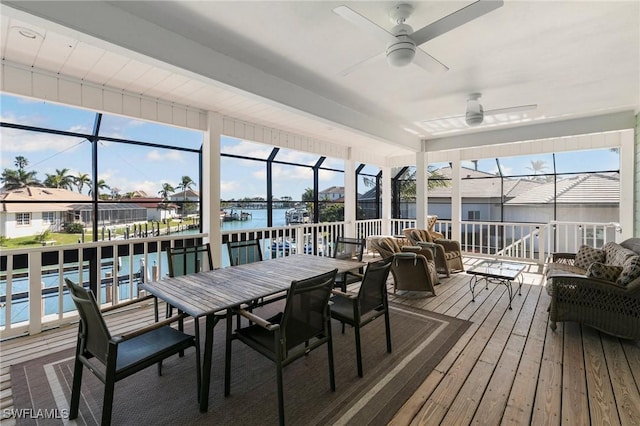 sunroom / solarium with ceiling fan and a water view