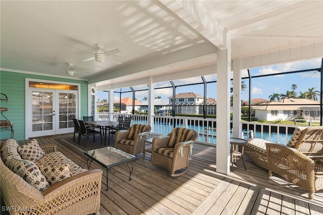 sunroom featuring french doors, a water view, and ceiling fan