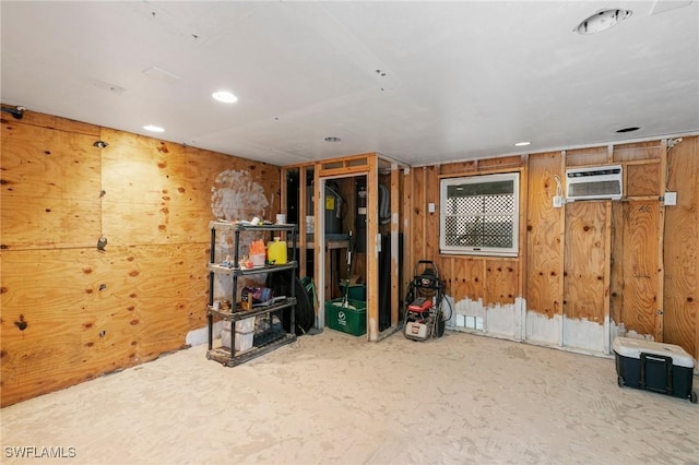 basement with a wall unit AC and wooden walls