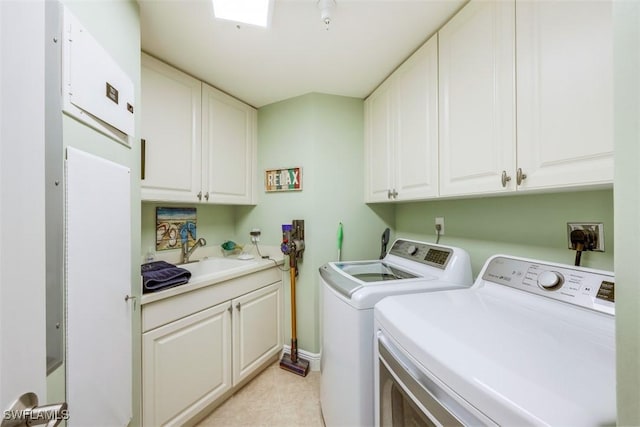 clothes washing area with a skylight, sink, separate washer and dryer, and cabinets