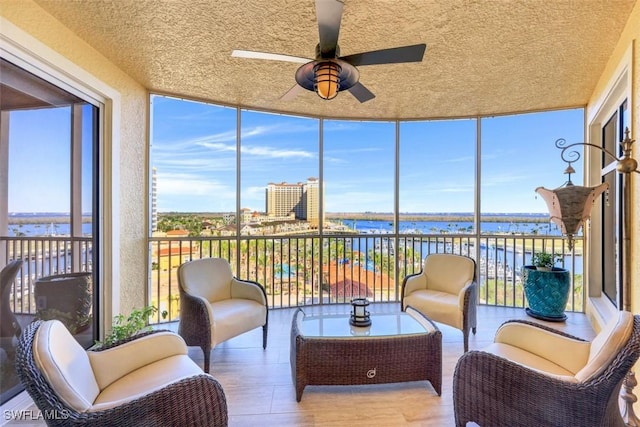 sunroom / solarium featuring ceiling fan, a wealth of natural light, and a water view