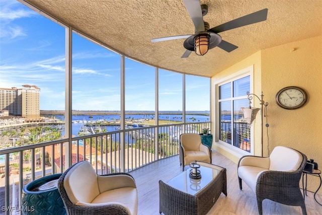 sunroom / solarium with ceiling fan, a wealth of natural light, and a water view