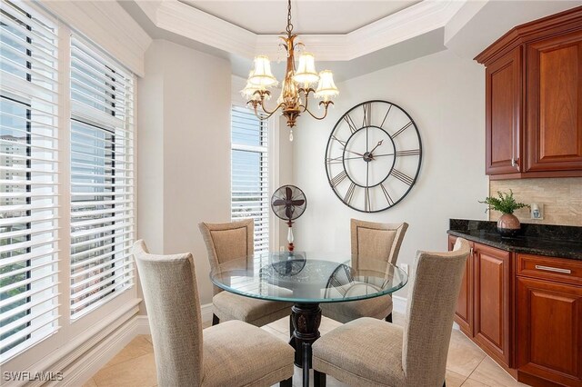 dining area featuring a raised ceiling, a wealth of natural light, a notable chandelier, and light tile patterned flooring