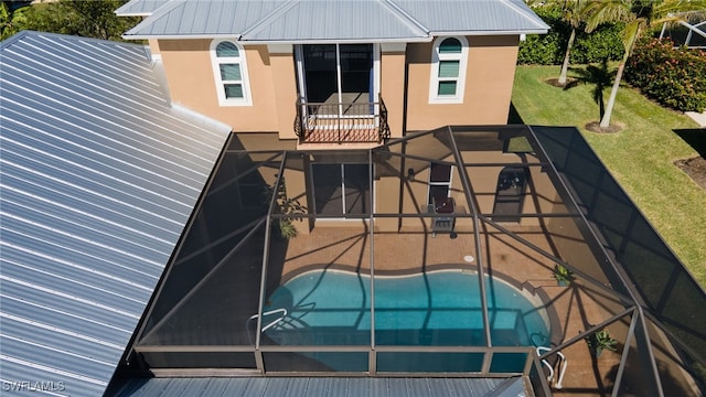 rear view of house featuring a lanai, a lawn, and a patio