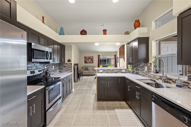 kitchen featuring kitchen peninsula, appliances with stainless steel finishes, dark brown cabinets, sink, and light tile patterned floors