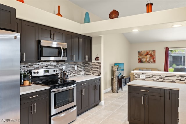 kitchen featuring vaulted ceiling, light tile patterned floors, tasteful backsplash, dark brown cabinets, and stainless steel appliances