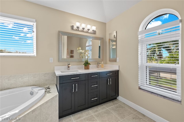 bathroom with tile patterned flooring, vanity, tiled bath, and vaulted ceiling