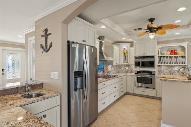 kitchen with white cabinetry, sink, stainless steel appliances, light stone countertops, and wall chimney range hood