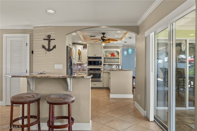 kitchen featuring pendant lighting, crown molding, appliances with stainless steel finishes, tasteful backsplash, and light stone countertops