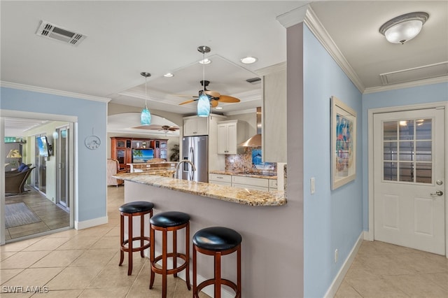 kitchen with wall chimney range hood, ornamental molding, white cabinets, stainless steel fridge with ice dispenser, and kitchen peninsula