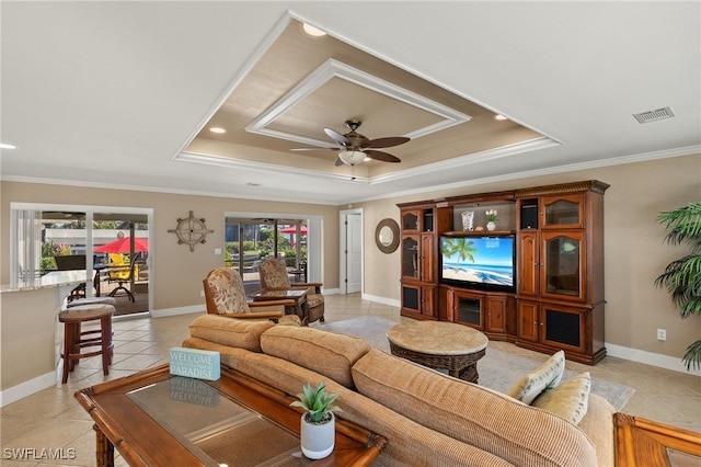 tiled living room with ornamental molding, a raised ceiling, and ceiling fan