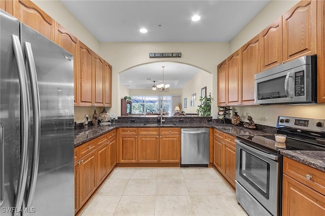 kitchen featuring a notable chandelier, dark stone countertops, sink, and stainless steel appliances