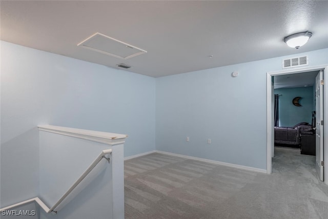 spare room featuring a textured ceiling and light carpet