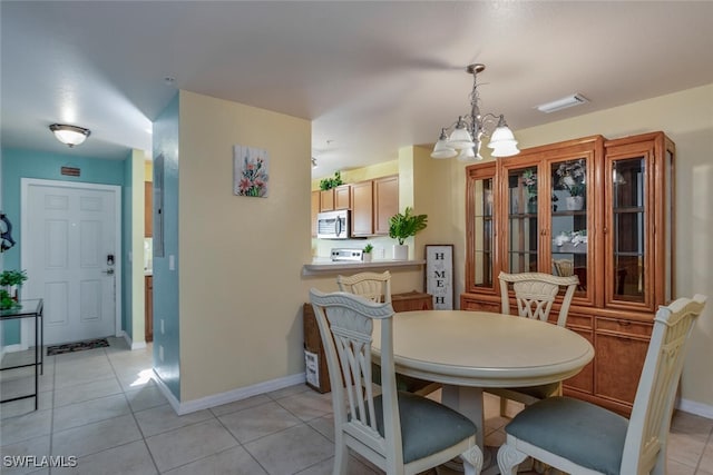 dining area featuring a chandelier and light tile patterned flooring