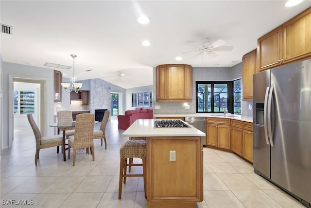 kitchen featuring appliances with stainless steel finishes, sink, decorative light fixtures, a center island, and a breakfast bar area