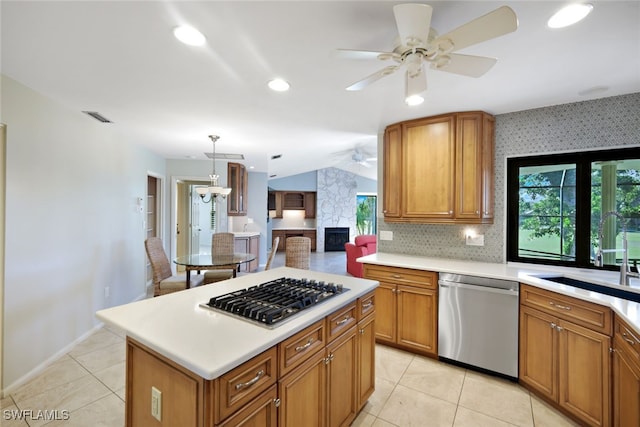 kitchen with stainless steel appliances, sink, light tile patterned floors, a center island, and hanging light fixtures