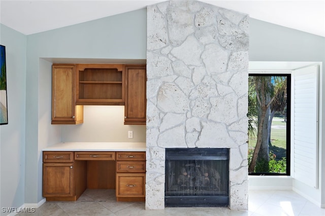 interior space with built in desk, a fireplace, and vaulted ceiling