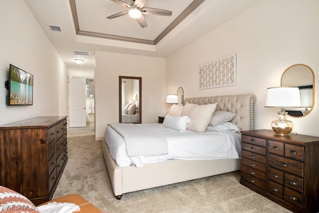 bedroom with a raised ceiling, crown molding, light carpet, and ceiling fan