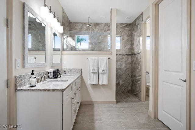 bathroom with vanity, tiled shower, and toilet