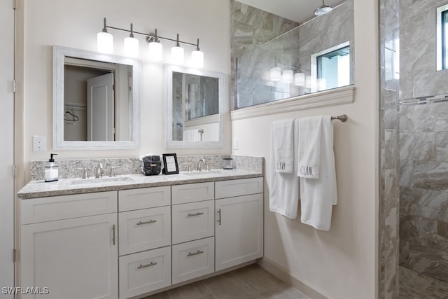 bathroom featuring a tile shower, vanity, and tile patterned floors