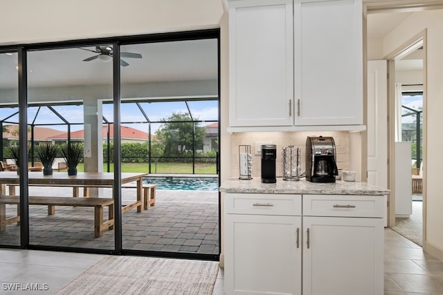 kitchen featuring a healthy amount of sunlight, white cabinets, light stone counters, and decorative backsplash