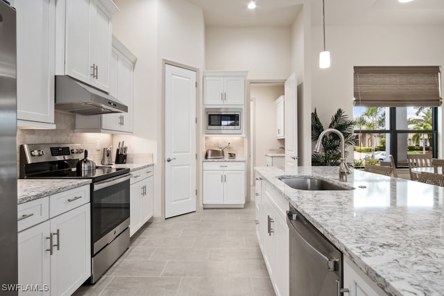 kitchen featuring sink, light stone counters, hanging light fixtures, appliances with stainless steel finishes, and white cabinets